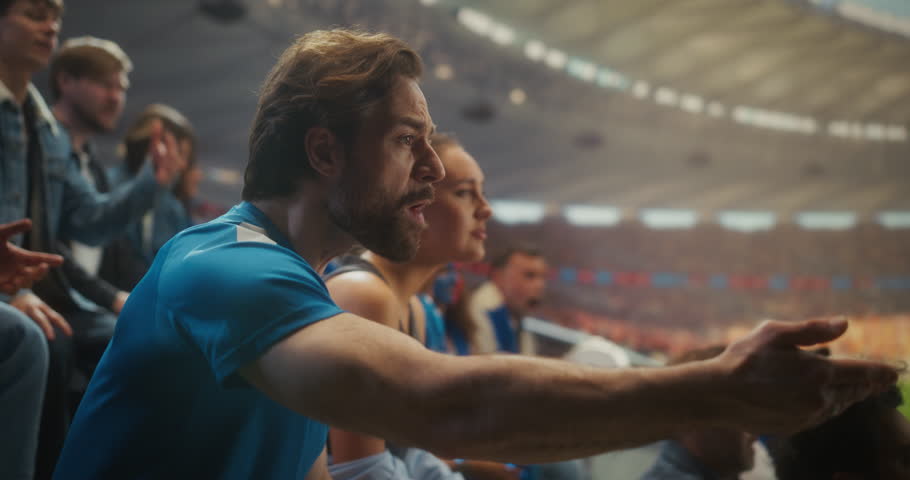Devastated Sports Fans in Blue React to a Painful Loss in a Huge Open Stadium as Man Grabs His Head in Disbelief and Nearby Supporters Slump, Frustration, and Anger. Losing Match and Game