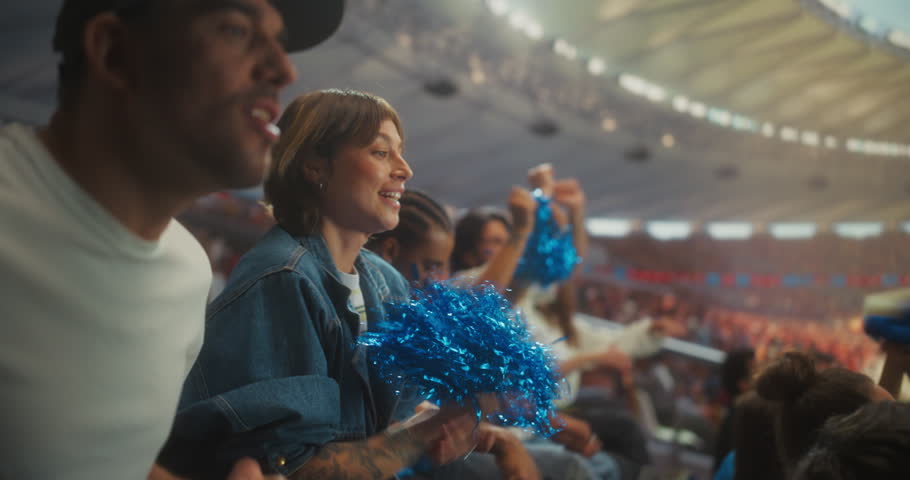 Diverse Soccer Fans Erupt in Championship Excitement Inside a Packed stadium Clapping, Waving Blue Pom-poms and Raising Arms as the Crowd Roars Through a Thrilling Match Atmosphere.