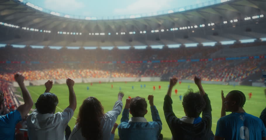 Back view Soccer Supporters Celebrate in a Packed Stadium, Raising Arms and Clapping During a Professional International Championship Match Game at a Major World Tournament Event