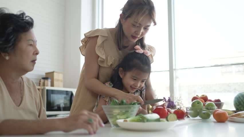 Daughter, mother and grandmother are preparing food together in the kitchen. Relationship, family, domestic life.
