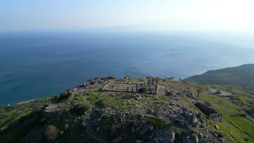 Aerial view of the ancient Temple of Athena ruins on the acropolis of Assos (Behramkale) over the Aegean Sea in Canakkale, Turkey. 4K resolution stock footage.