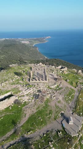 Aerial view of the ancient Temple of Athena ruins on the acropolis of Assos (Behramkale) over the Aegean Sea in Canakkale, Turkey. 4K resolution stock footage.