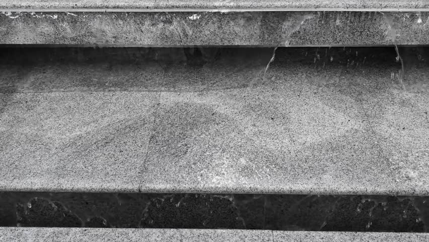 Water is flowing down the steps. Stones make up the steps. They have different patterns and textures. Some areas are flat while others show lines. The steps go both up and down, showing vertical and horizontal views.