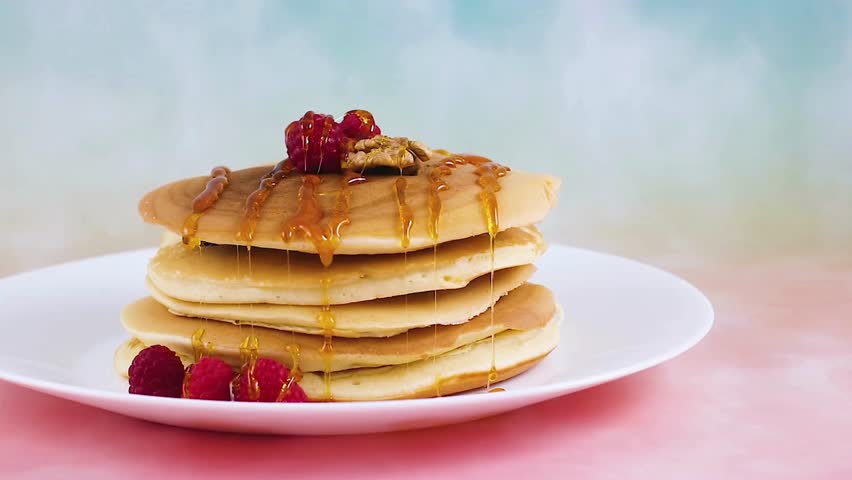 Tasty homemade pancakes with syrup and raspberries for morning breakfast. adds raspberries and syrup to pancake, uses new morning breakfast recipe.