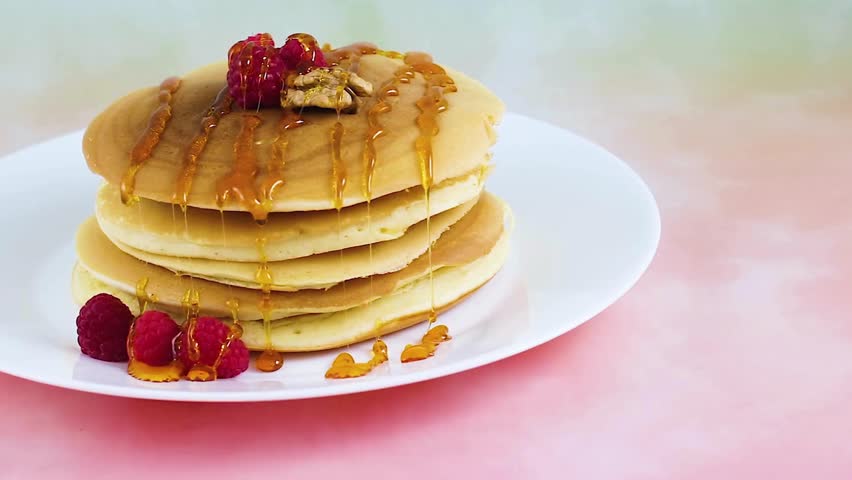 putting honey or jam on pancakes with raspberries. tasty pancakes with berries. A stack of fluffy breakfast American pancakes with fresh raspberries.