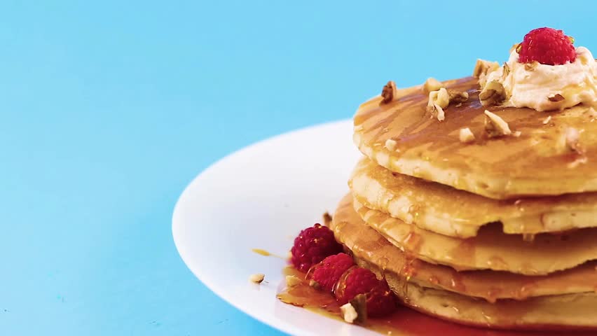 adds raspberries and syrup to pancake, use new easy breakfast recipe. putting maple syrup on pancakes with raspberries. tasty pancakes with berries.