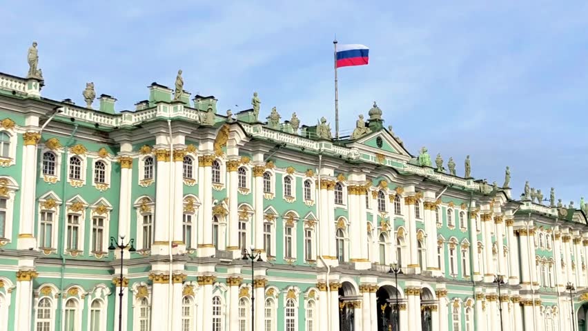 Saint Petersburg, Russia – March 8, 2026: View of the Winter Palace and the State Hermitage Museum on Palace Square with people walking in spring weather and the Russian flag flying above the historic building. Iconic city landmark in 16:9 format