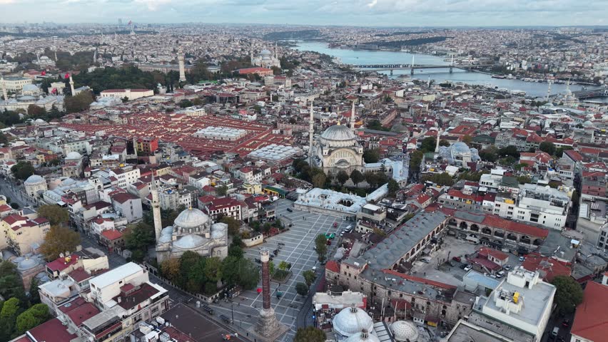 Aerial view approaching the Grand Bazaar and Nuruosmaniye Mosque in Istanbul, Turkey, with the Golden Horn and Bosphorus Strait in the distance.