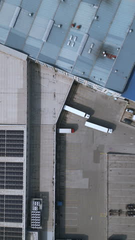 Three trucks are parked in a designated area of a distribution warehouse. The trucks are lined up neatly in the parking lot, ready for freight transportation.