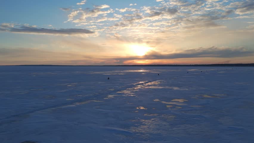 Majestic sunset with a snowmobile driving over a frozen Lake Superior during winter