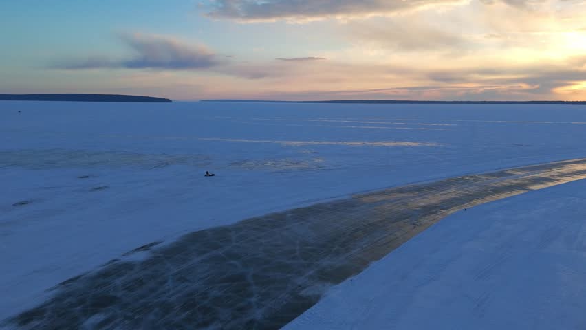 Sunrise over frozen Lake Superior during a majestic winter morning with a person standing on the ice and snow