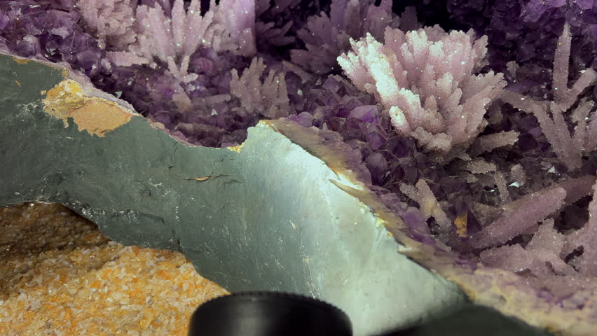 Amethyst geode interior featuring delicate pale crystal formations among purple clusters in a detailed close-up shot