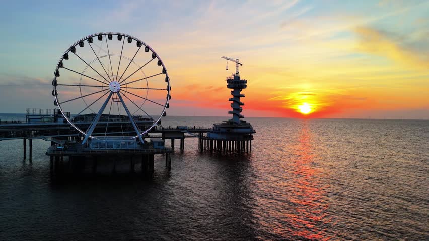 Sunset on the beach in The Hague, Netherlands. The North Sea coast, Scheveningen Pier and the famous Ferris wheel SkyView de Pier.	
