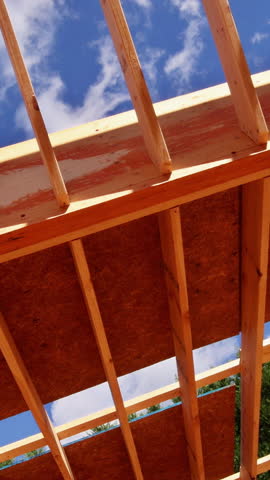 Workers are building wooden beams rafters roof frame in home construction.