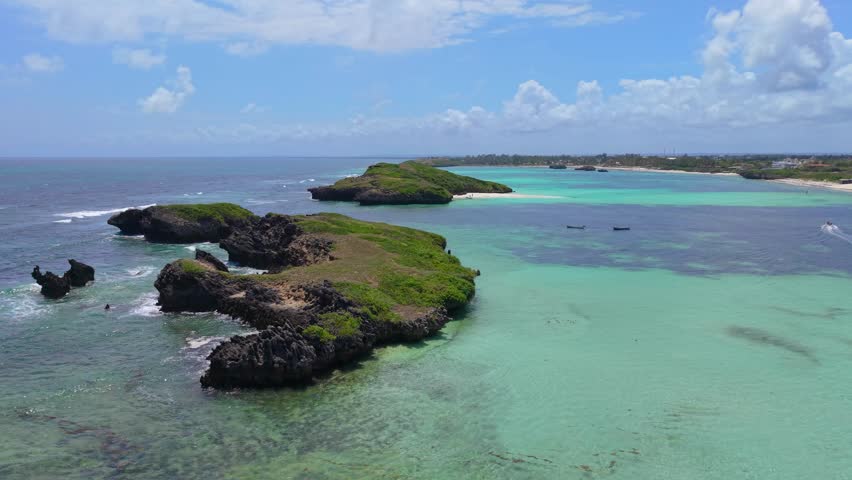 Aerial view of rocky islets and turquoise ocean water along the coastline with white sand and coral reefs at Watamu Beach, Kenya.