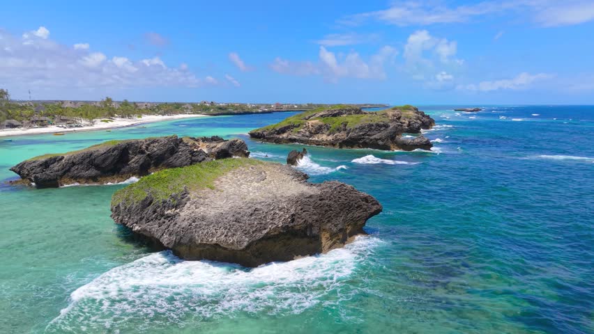 Aerial view of rocky islets surrounded by turquoise ocean water and white sand beach along the coastline of Watamu Beach, Kenya.