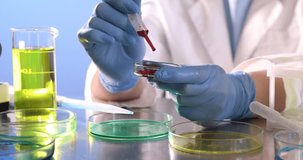 Scientist dripping liquid sample into Petri dish at table, closeup - Powered by Shutterstock - Get 15% off with code: PIKWIZARD15