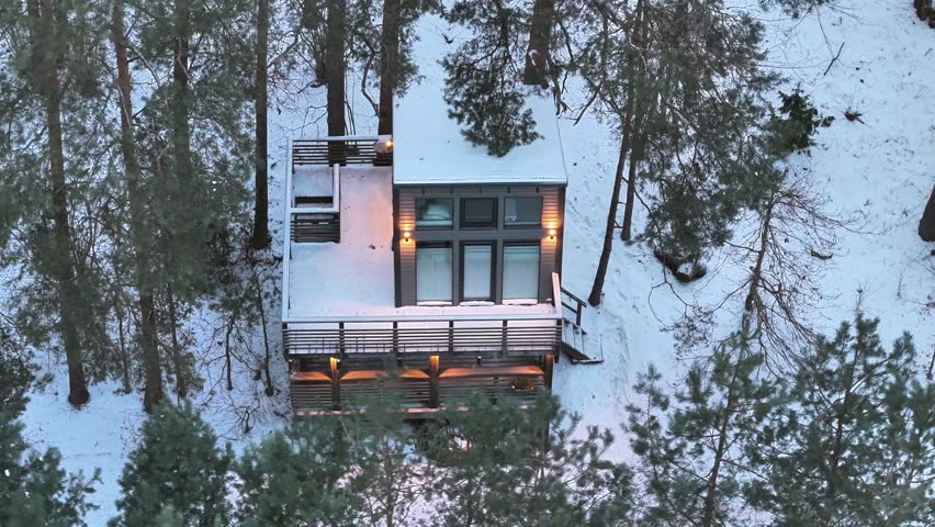 Aerial capture of modern cabin nestled in winter forest