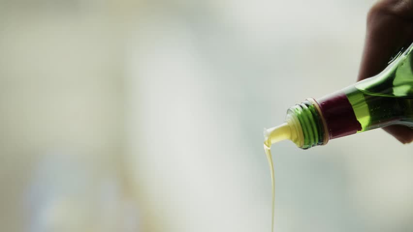 Olive Oil Pouring From Bottle, Golden Olive Oil Liquid Flowing From Green Bottle Neck, Healthy Olive Oil Stream Dripping From Glass Bottle For Cooking, Natural Vegetable Fat Dressing For Salad, Pure Organic Ingredient Falling Down, Yellow Fluid Motion In Kitchen, Culinary Preparation Process Background, Extra Virgin Product Quality, Hand Holding Container Over Dish, Nutrition Wellness Meal Component, Clear Sunlight Reflection On Flow, Mediterranean Diet Lifestyle Essence