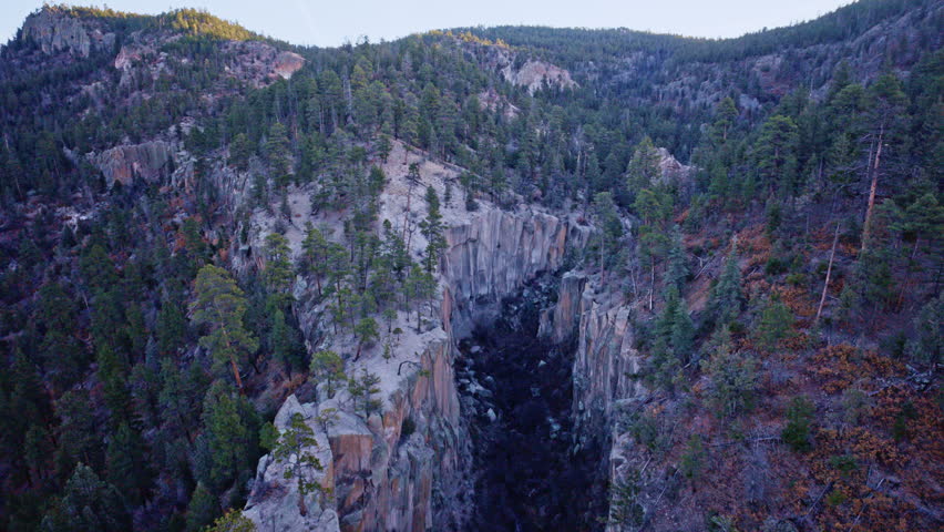 Cinematic drone shot of rugged cliffs and canyon terrain near Los Alamos, New Mexico