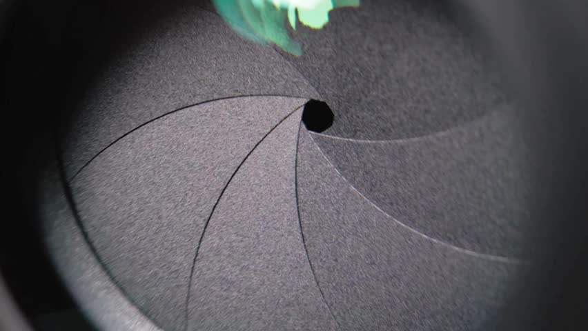 Shot of Diaphragm blades of fixed camera lens opening and closing aperture. Closing and opening Aperture of film camera. Camera lens aperture close-up.