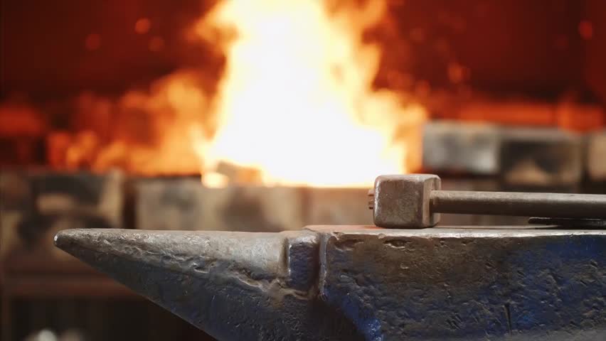 Worker in a forge workshop handling metal forging on an anvil while throwing waste into a furnace, highlighting industrial metalwork and waste incineration.