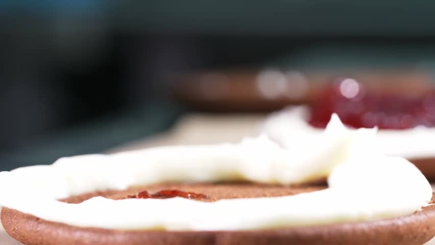Strawberry jam being added to a mini chocolate cake, creating a sweet dessert with rich chocolate and fruity topping in close-up detail.