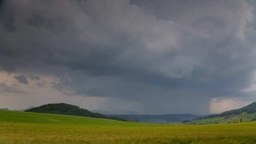 Dramatic Dark Storm Clouds Over Green Rural Fields and Mountains