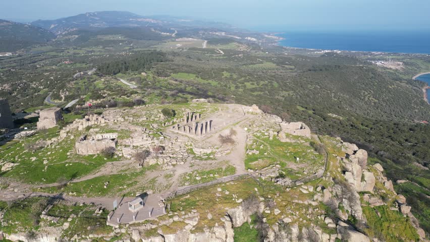 Aerial view of the ancient Temple of Athena ruins on the acropolis of Assos (Behramkale) over the Aegean Sea in Canakkale, Turkey. 4K resolution stock footage.