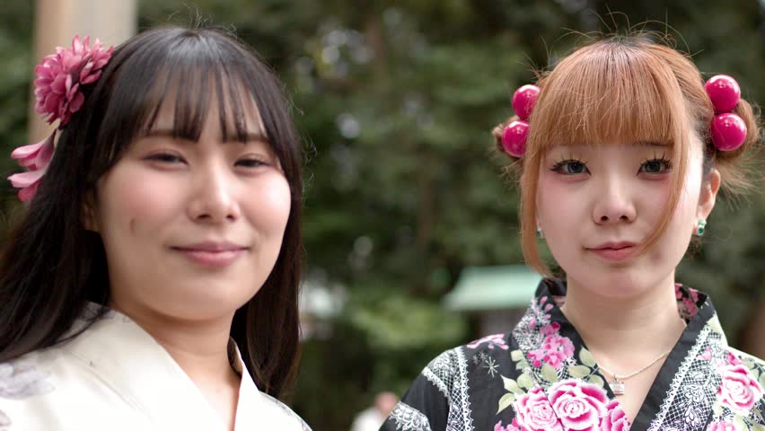 Close-up portrait of two young Japanese women wearing traditional kimonos at a Shinto shrine