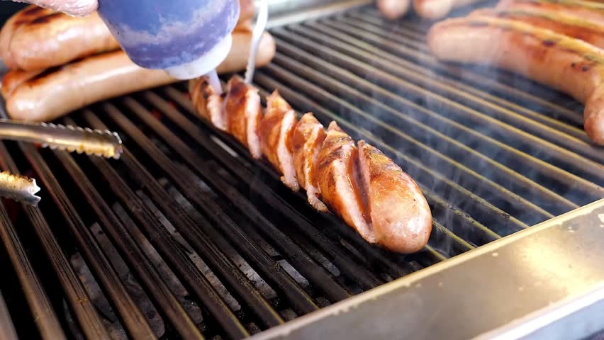 A close-up shot of a juicy, spiral-cut sausage grilling on a professional barbecue. A chef
