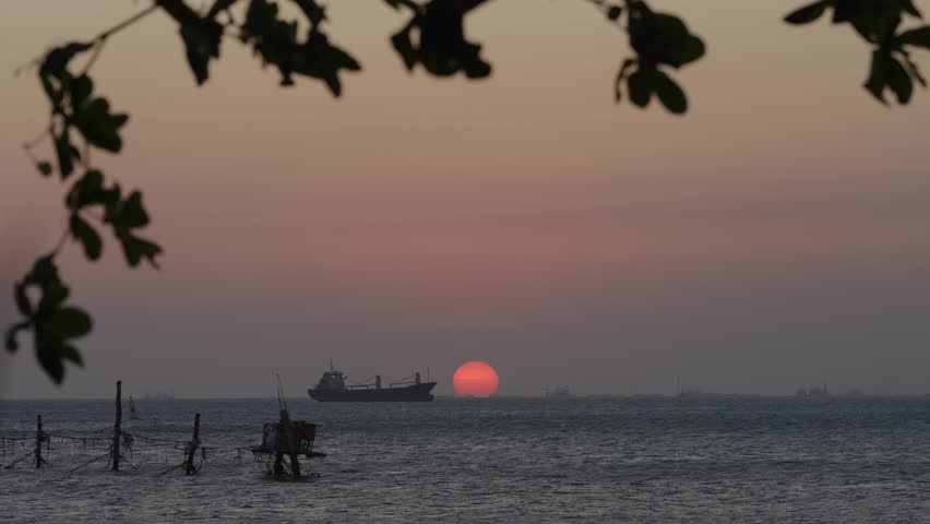Sunset over ocean with red sun near horizon, peaceful seascape for travel and background use