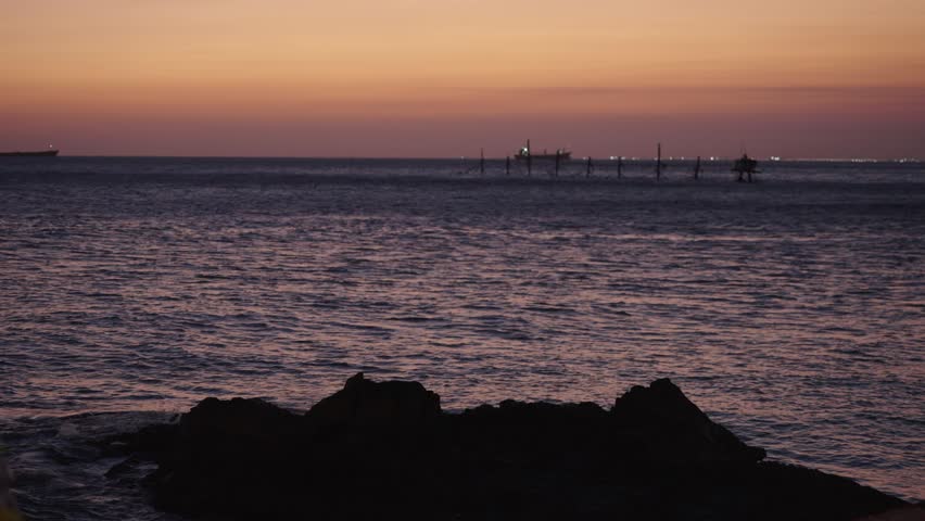 Coastal scene with rocks in foreground and ocean sunset horizon, natural landscape for travel and environmental themes