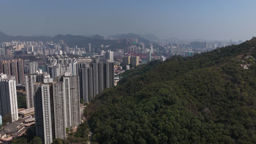 Aerial view of hong kong cityscape bordering lush green mountains