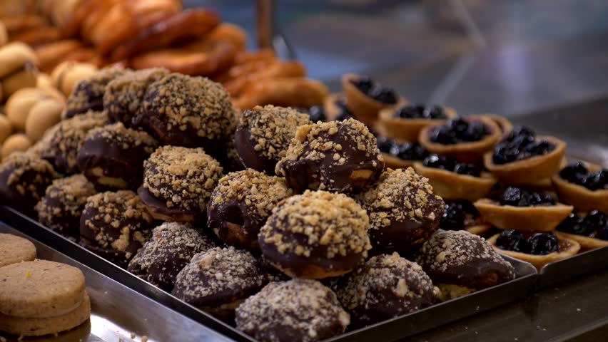 Chocolate covered biscuits with sprinkles on top. Artisanal pastry shop. Panning 4K