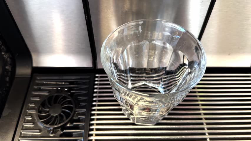 Coffee pouring into glass cup from WMF coffee machine, top view.