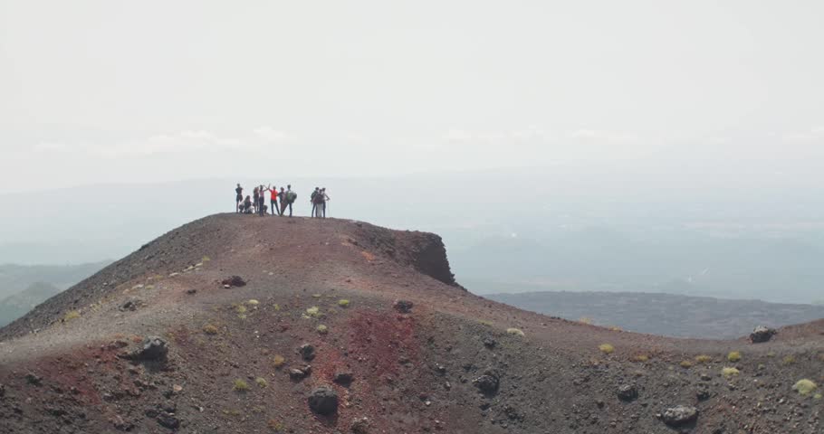 Group of hikers standing on a hill overlooking the valley near Etna Volcano, 4k