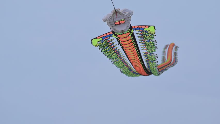 slow motion of a dragon shaped kite flying in the sky beautifully.