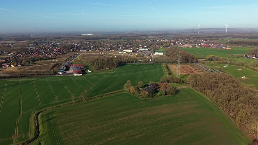 Rural farmland fields and small American town during sunny day and blue sky in spring season. Aerial establishing shot. Peaceful and quiet suburb area in different colors. Countryside city in USA .