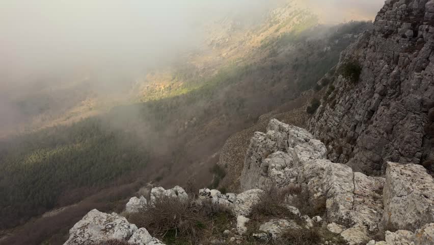 Rugged Mountain Landscape Covered in Clouds - Tilt Up
