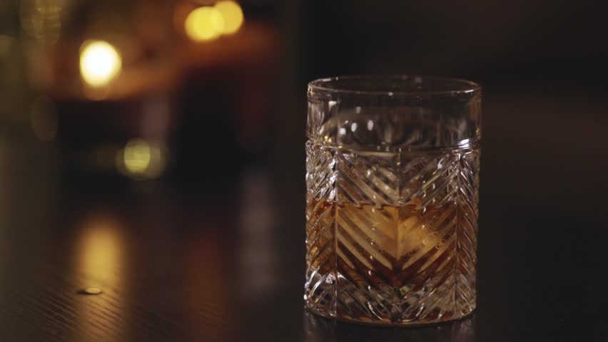 Bartender Mixing The Whisky With Ice Cube Using A Bar Spoon. - closeup shot