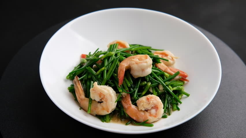 Stir-Fried Shrimps with Chinese Chives flower in white plate.