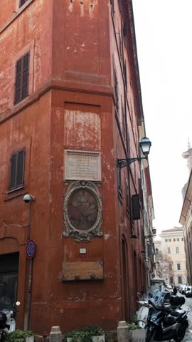 Historic red building corner with aged plaster facade and architectural details, urban environment.