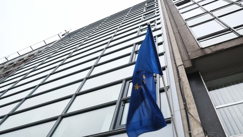 EU Blue Flag With Yellow Stars Fluttering On A Pole Of Building