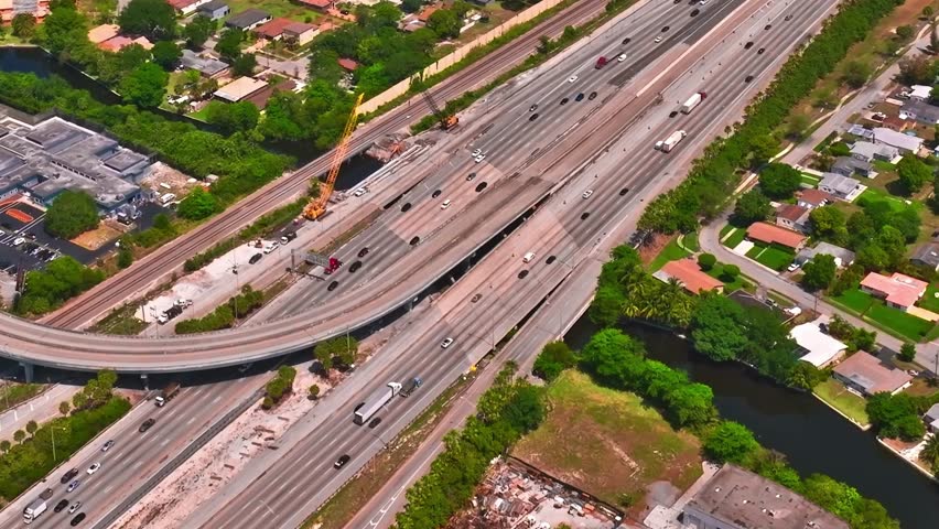 The layout of highways and residential areas in Miami, USA. Cars travel along the roads while buildings and trees are visible nearby.