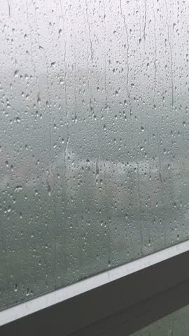 Rain drops on window. Rainy weather. Closeup. Vertical footage
