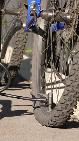Man inflating bicycle tire outdoors. Pumping up bike tire. Closeup. Vertical footage
