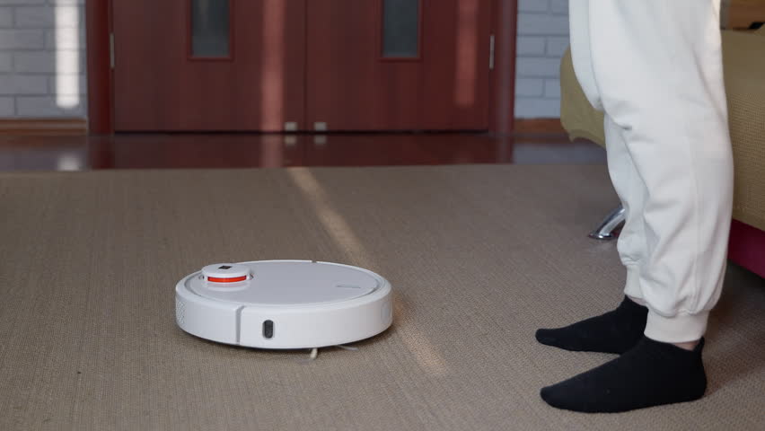 Robot vacuum cleaner cleaning carpet near person
