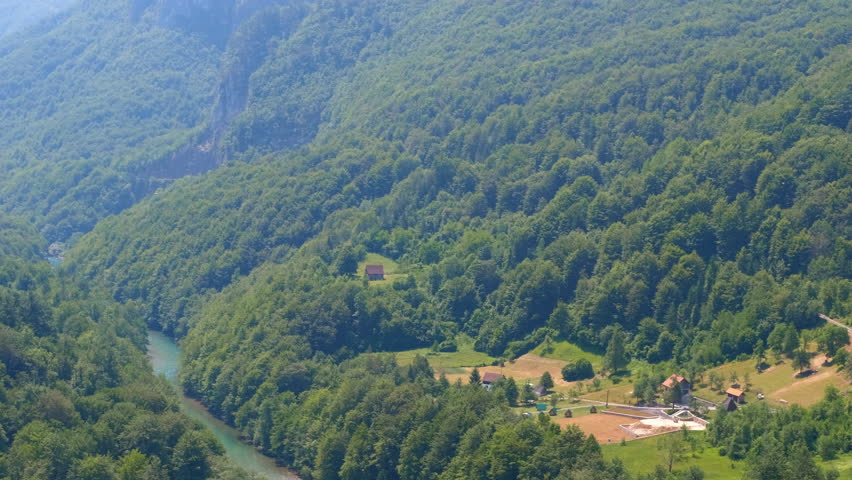 Lush green tara river canyon panning across the valley. Stunning panoramic view of the tara river canyon. Panning from the turquoise water flowing through the deep valley to a charming village