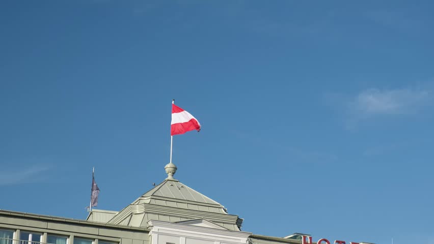 Low angle shot of the national flag of Austria waving on top of a classic building roof in Salzburg, Austria, Europe.